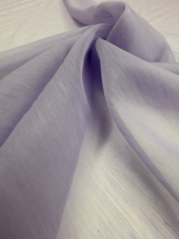 Close-up of Super Cheap Fabrics' Designer Voile in Pastel Lilac (150cm), showing soft folds and gentle shadows. The semi-transparent, lightweight fabric has a smooth, flowing texture.