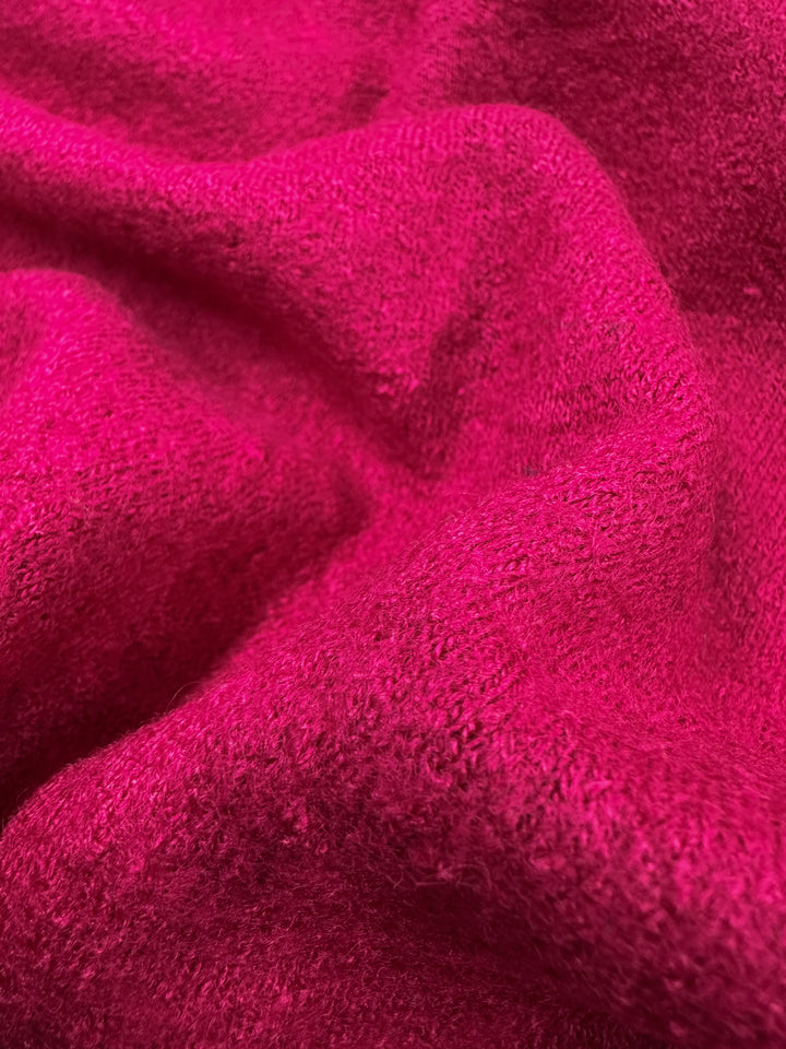 A close-up of Boiled Wool - Vivacious from Super Cheap Fabrics showcases its bright pink, soft, fuzzy texture with gentle folds and creases, crafted from a luxurious wool-viscose blend. Width: 145cm.