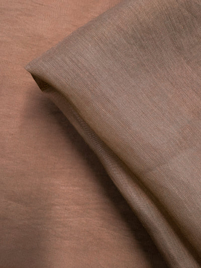 Close-up of Super Cheap Fabrics' Designer Voile - Burro - 150cm in light brown, showcasing its extra lightweight, sheer quality and soft, smooth texture with gentle folds for an elegant look. Subtle weave adds to its refined appeal.