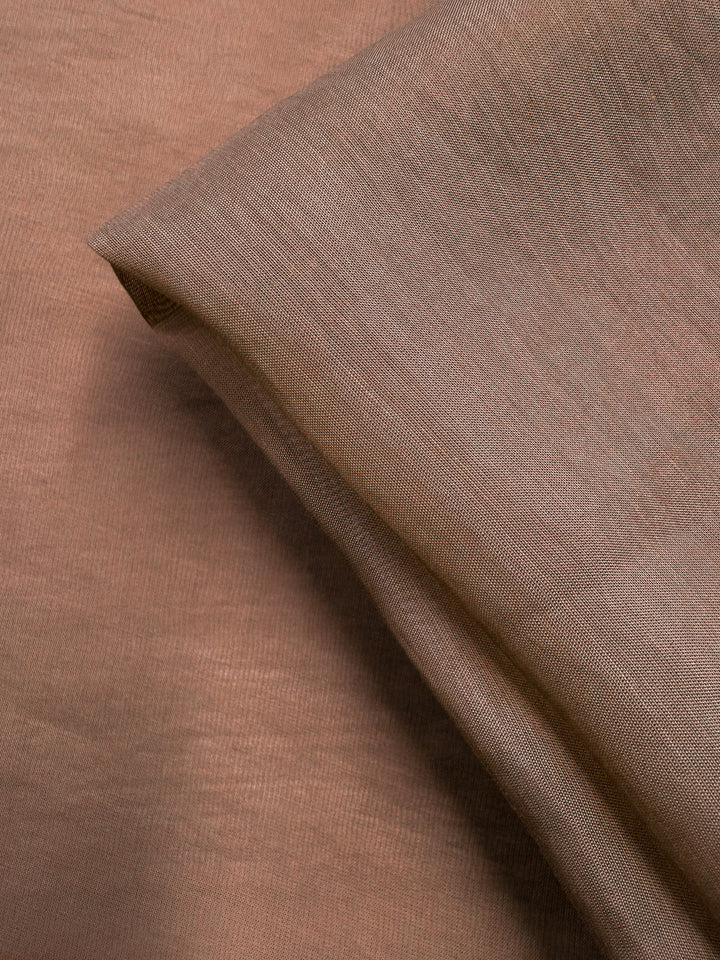Close-up of Super Cheap Fabrics' Designer Voile - Burro - 150cm in light brown, showcasing its extra lightweight, sheer quality and soft, smooth texture with gentle folds for an elegant look. Subtle weave adds to its refined appeal.