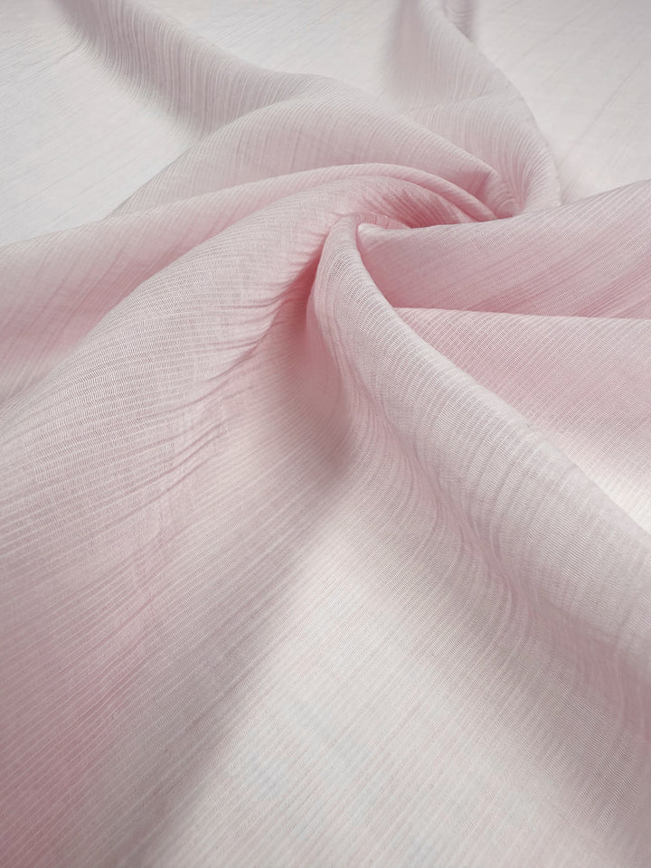 A close-up of Super Cheap Fabrics' Textured Designer Voile - Carinaria (155cm), showcasing its soft, pale pink lightweight cotton with subtle texture—ideal for creating sheer summer dresses.