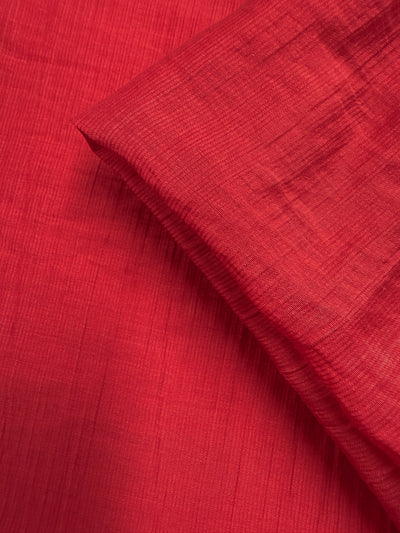 A close-up of Super Cheap Fabrics' Textured Designer Voile - True Red (155cm) shows its lightweight, finely textured weave. A folded section casts a soft shadow, highlighting the delicate detail and summer appeal of this fabric.
