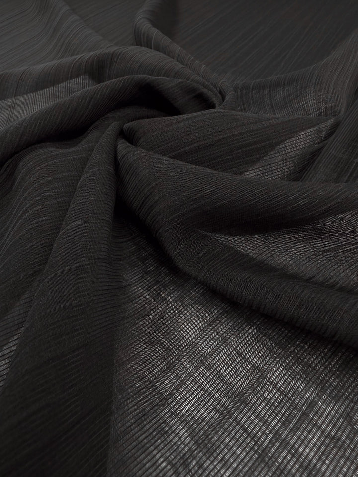 Textured Designer Voile - Black by Super Cheap Fabrics features fine horizontal lines and gentle folds, offering a semi-transparent look—ideal for lightweight summer dresses. Width: 155cm.