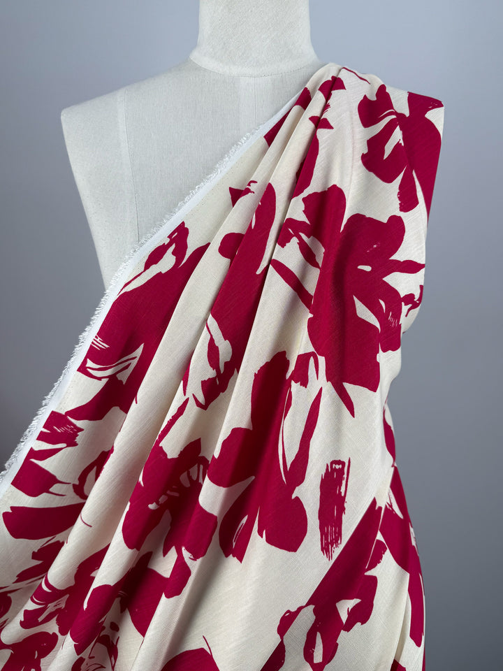 A white dress form displays Super Cheap Fabrics’ Bamboo Rayon - Crimson Bloom - 150cm, a cream, lightweight fabric with bold red florals, set against a plain light gray background.