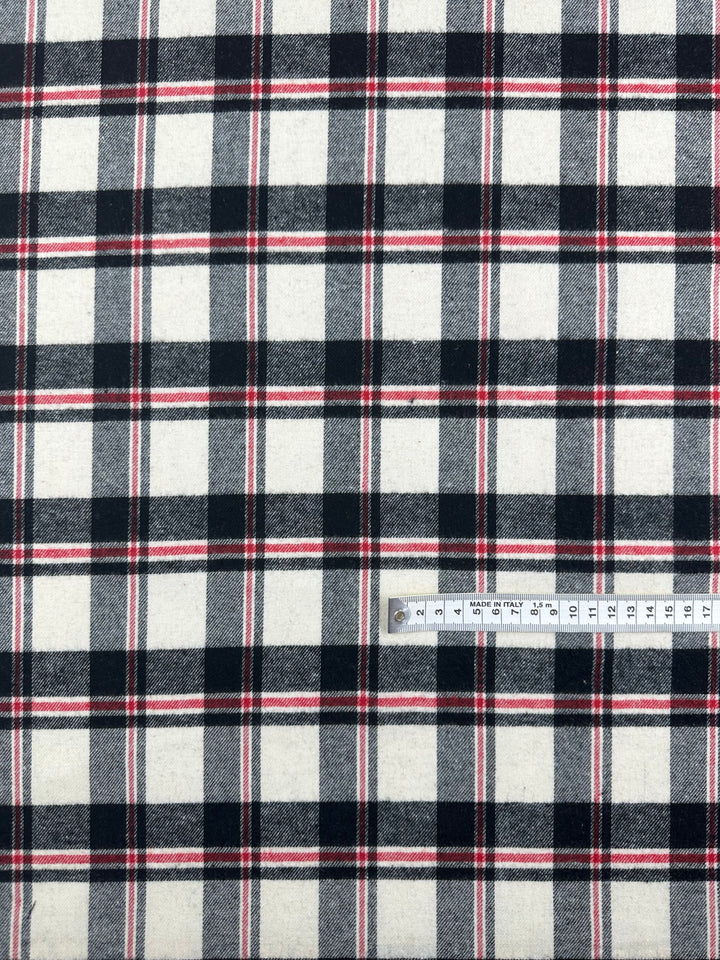 A ruler measures the "Suiting - Black Watch Plaid - 147cm" by Super Cheap Fabrics, a cotton polyester fabric with a plaid pattern in black, white, and red. The ruler displays measurements in centimeters.