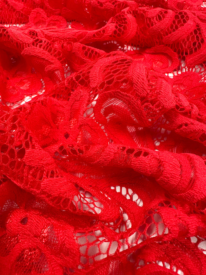 Close-up of Super Cheap Fabrics' Designer Lace in Scarlet, featuring intricate floral patterns and mesh details. The delicate 145cm fabric highlights solid and openwork areas, ideal for elegant evening dresses.