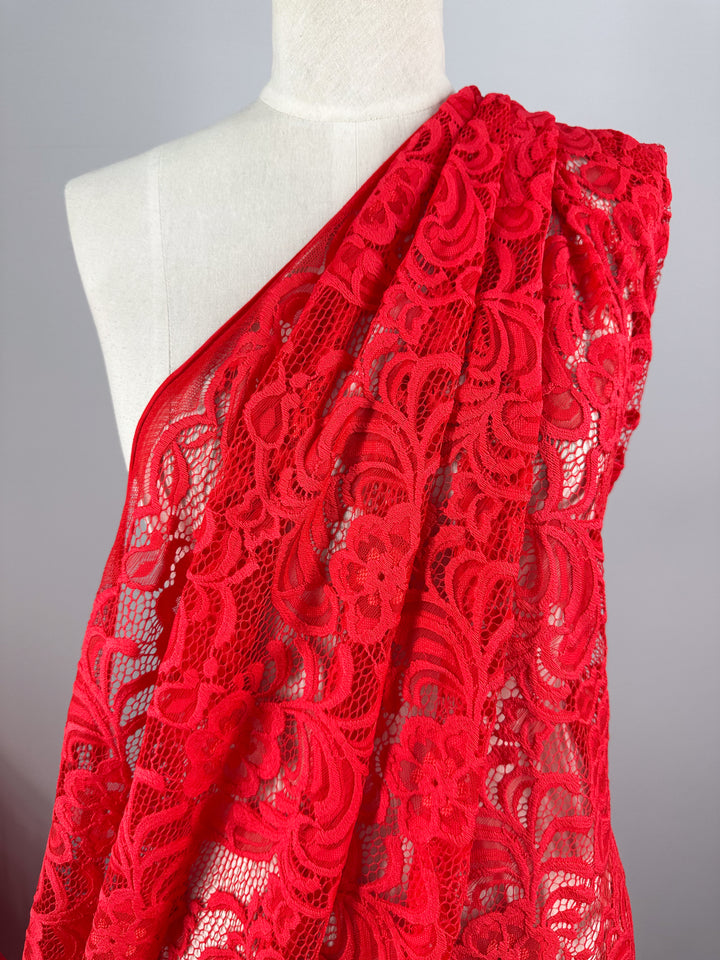 A mannequin displays the Designer Lace - Scarlet from Super Cheap Fabrics, draped diagonally to highlight its intricate floral design.