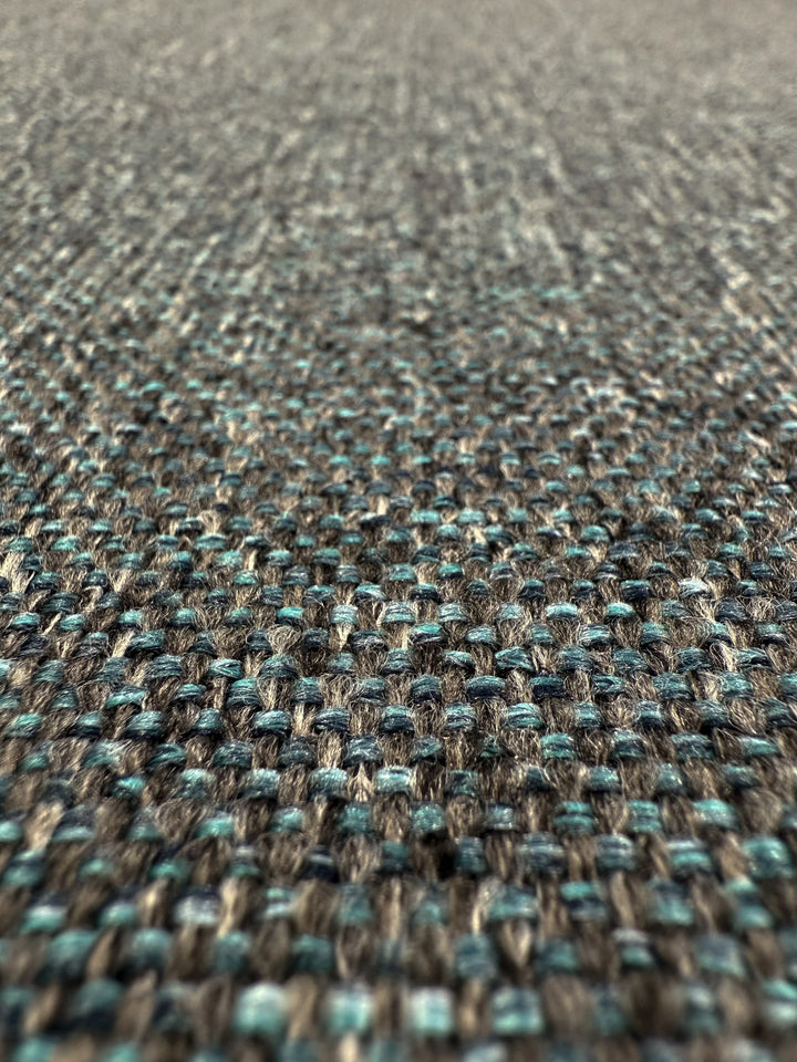 Close-up of Super Cheap Fabrics' Upholstery - Soho Topaz- 150cm, a medium weight fabric with a textured pattern and interlaced blue, gray, and beige threads seen from a low angle.