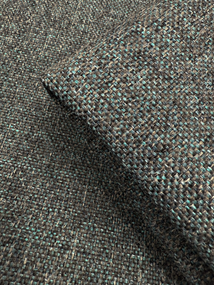 Close-up of Soho Topaz upholstery fabric by Super Cheap Fabrics, 150cm wide, with textured woven brown and teal threads—a medium weight ideal for upholstery. Folded corner highlights coarse, interlaced texture.